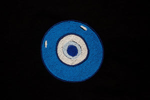 Embroidered blue evil eye. Featured on a black backrgound.