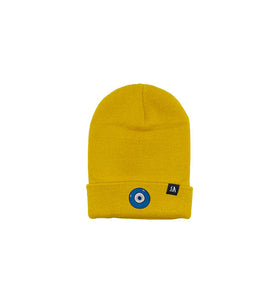 Blue Evil Eye embroidered on a mustard yellow acrylic beanie, with an RA Attire woven logo label. Featured on white background image.