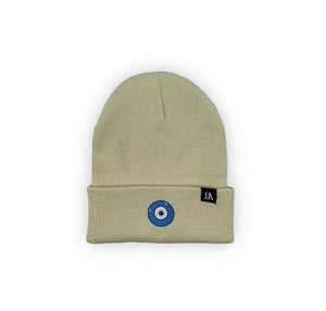 Blue Evil Eye embroidered on a sand / beige acrylic beanie, with an RA Attire woven logo label. Featured on white background image.