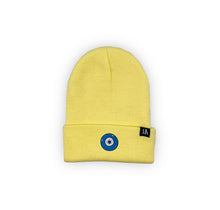 Load image into Gallery viewer, Blue Evil Eye embroidered on a light butter yellow acrylic beanie, with an RA Attire woven logo label. Featured on white background image.