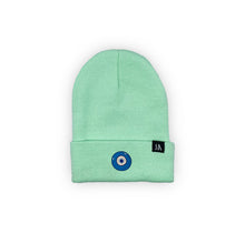 Load image into Gallery viewer, Blue Evil Eye embroidered on a mint green acrylic beanie, with an RA Attire woven logo label. Featured on white background image.